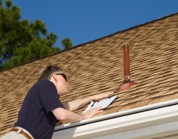 Carver roofer inspecting roof shingles for summer maintenance