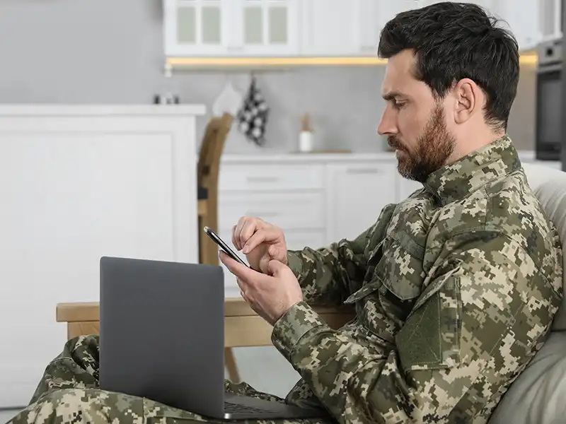 Military personnel at home using their laptop and phone in their living room